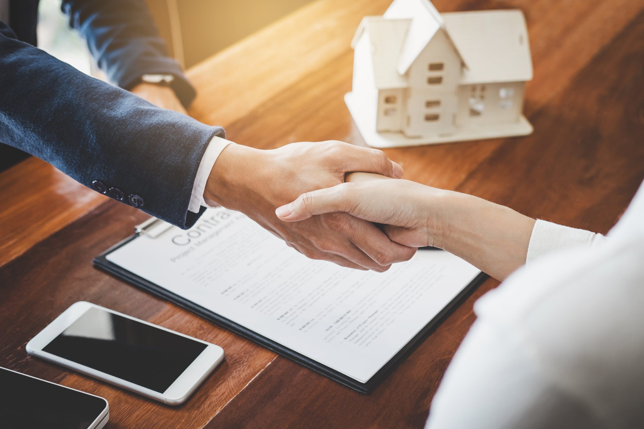 Shaking hands over contract and model house